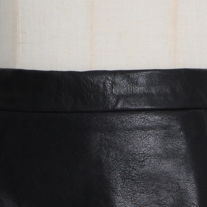 Detailed macro view of black pleated leather skirt waist with fine stitching
