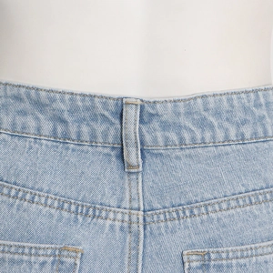 Macro view of light blue denim jeans showing reinforced stitching and back pocket details