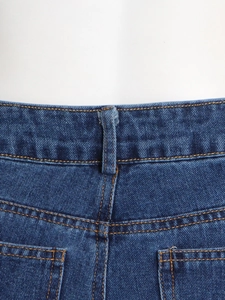 Vista detallada de la cintura y los bolsillos traseros en denim azul oscuro con costuras amarillas