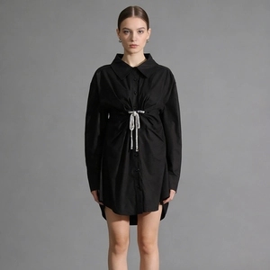 Détail de la robe chemise noire à manches longues avec boucle nœud en strass et plis