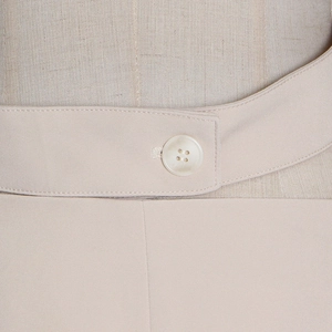 Detail of waist design with color-matched button and twill fabric texture on beige blazer