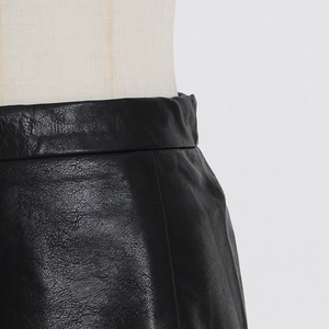 Detailed view of high-waist pleated leather skirt featuring premium texture and mesh stitching