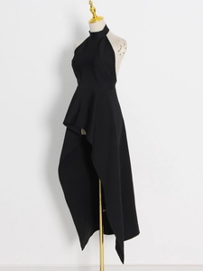Detail of black halter neck dress with peplum waist and asymmetric fishtail hem