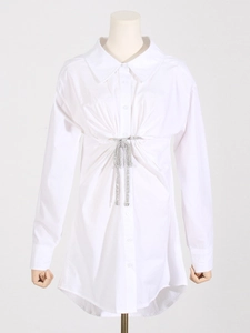 Détail d'une robe chemise blanche avec taille plissée et nœud en strass étincelants