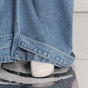 Close-up of adjustable drawstring hem and stitching on blue denim cargo pants