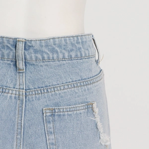 Close-up of high-waisted light blue denim jeans with distressed pocket fringe detail