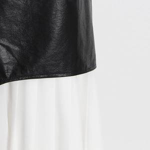 Detail of high-waisted pleated skirt showing black leather and white mesh splicing