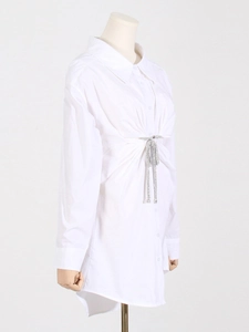 Vue détaillée d'une robe chemise blanche avec nœud en strass et taille plissée élégante
