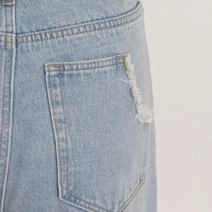 Detail of light blue denim cargo pants with fringed pocket and vintage style texture