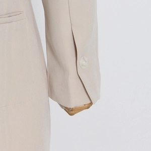 Detail shot of light beige blazer cuff with resin button and smooth premium fabric