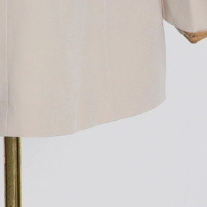 Close-up of the beige suit jacket hem showing fine fabric texture and straight tailoring