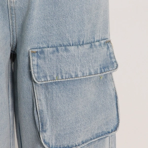 Detail of light blue cargo jeans showing denim texture and yellow stitching on pocket