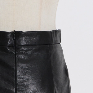 Close-up of high-waist pleated leather skirt featuring fine texture and invisible zipper