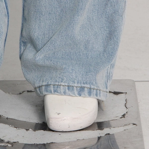 Detailed macro view of light blue denim fabric texture and leg hem of wide-leg cargo pants