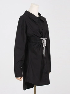 Détail des plis à la taille et nœud en strass argenté sur la robe chemise noire à manches