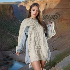 Detailed close-up of beige cable knit sweater with denim patchwork sleeves and drawstring hem