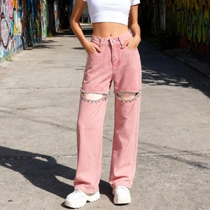 Dettaglio di jeans rosa a vita alta con ritaglio al ginocchio e catene di strass