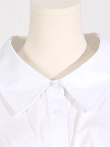 Détail du col à revers blanc et des boutons sur une robe de créateur à manches longues