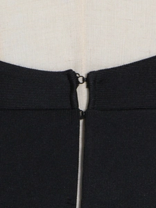 Macro detail of metal hook-and-eye closure on a black ribbed two-piece evening dress