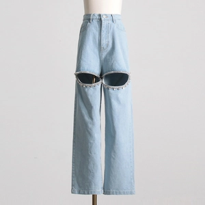 Dettaglio di jeans blu a vita alta con ritagli ovali e finiture in strass
