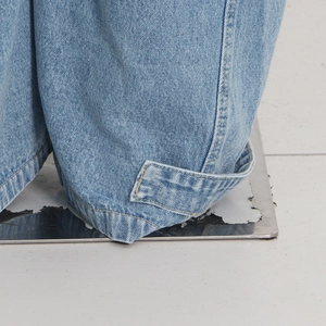 Close-up of contrast yellow stitching and strap detail on light blue denim cargo pants