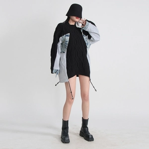 Detail of oversized knit sweater featuring denim patchwork and drawstring hem design