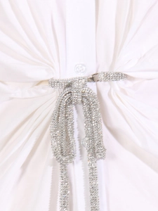 Détail de la taille d'une robe en coton blanc avec ceinture de strass luxueuse