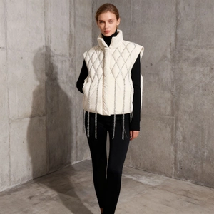 Detail of white quilted vest with rhinestone fringe chains and high stand collar for women