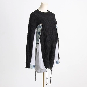 Detail view of black cable-knit sweater with denim patchwork and drawstring hem