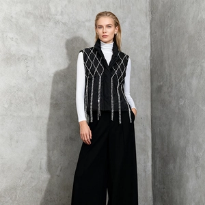 Detailed view of women's black quilted vest with rhinestones and elegant fringe hem