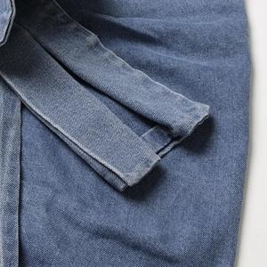 Détail du tissu denim bleu montrant la texture sergé et les coutures doubles durables