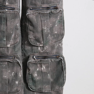 Détail du jean cargo gris délavé avec effet taches de peinture et poches zippées en métal