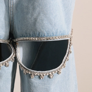 Dettaglio di jeans a vita alta blu chiaro con design cut-out e ciondoli a cuore