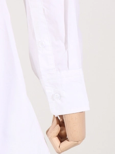 Détail du poignet d'une chemise blanche avec deux boutons translucides et coutures