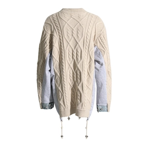 Detail showing cable knit texture with grey patchwork sleeves and metal button cuffs