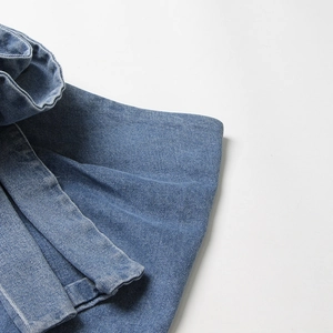 Gros plan détaillé montrant la texture du denim délavé et la coupe multicouche de la jupe