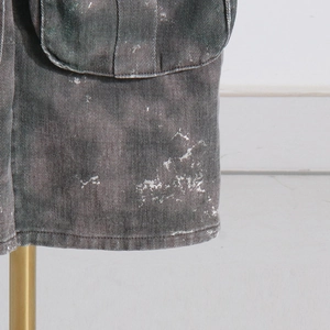 Détails du tissu de pantalon cargo camouflage avec éclaboussures de peinture blanche