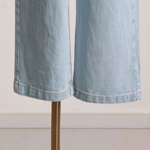Dettaglio ravvicinato dell'orlo dei jeans chiari con doppia cucitura pulita e trama denim