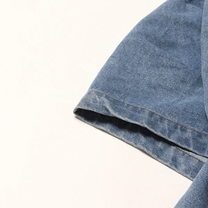 Détail de jupe en jean bleu montrant le tissage sergé et les surpiqûres orange