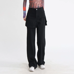 Dettaglio dei jeans neri a vita alta con gamba larga e design unico a strati tipo gonna