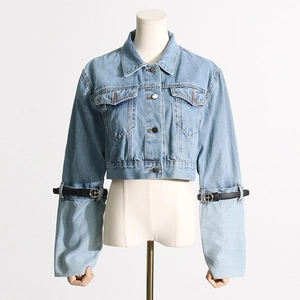 Detail view of denim jacket sleeve with black leather strap and silver metal ring buckle