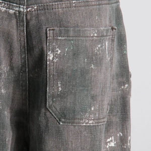 Vue détaillée de la poche arrière en denim gris foncé avec taches de peinture et délavage vintage
