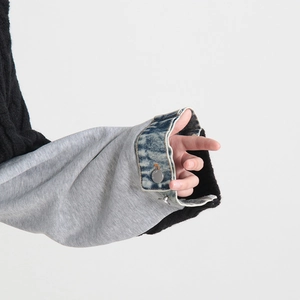 Detail of sleeve cuff showing grey sweatshirt fabric joined with denim and metal buttons