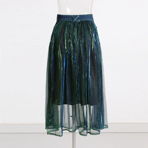 Close-up of iridescent green mesh skirt with pleated texture and denim high-waist detail