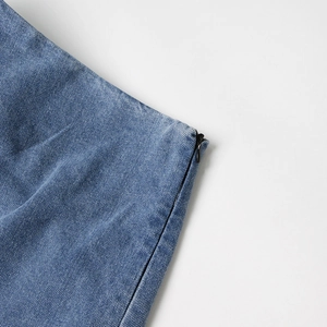 Détail d'une fermeture éclair invisible noire sur une mini-jupe en jean bleu clair