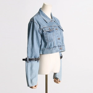 Detail of cropped denim jacket with unique buckle belt design on the sleeves