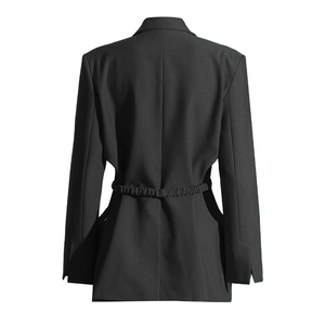 Détail de la découpe au dos et de la ceinture plissée sur une veste de costume noire