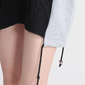 Detail of knit and denim patchwork hem with adjustable black drawstrings and metal beads