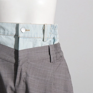 Détail de la taille double avec patchwork en jean et tissu à carreaux gris sur le pantalon