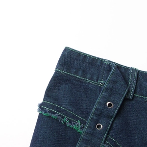 Detail of dark blue denim skirt with bright green contrast stitching and raw fringe edges